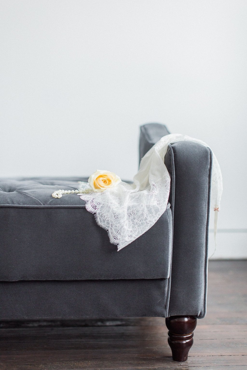 Lauren Renee Photography yellow rose laying on grey velvet couch with pearls