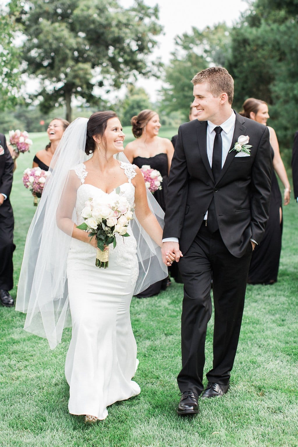 Lauren Renee - Pittsburgh Fine Art Wedding Photography Bride and groom walking and holding hands looking at each other with bridal party