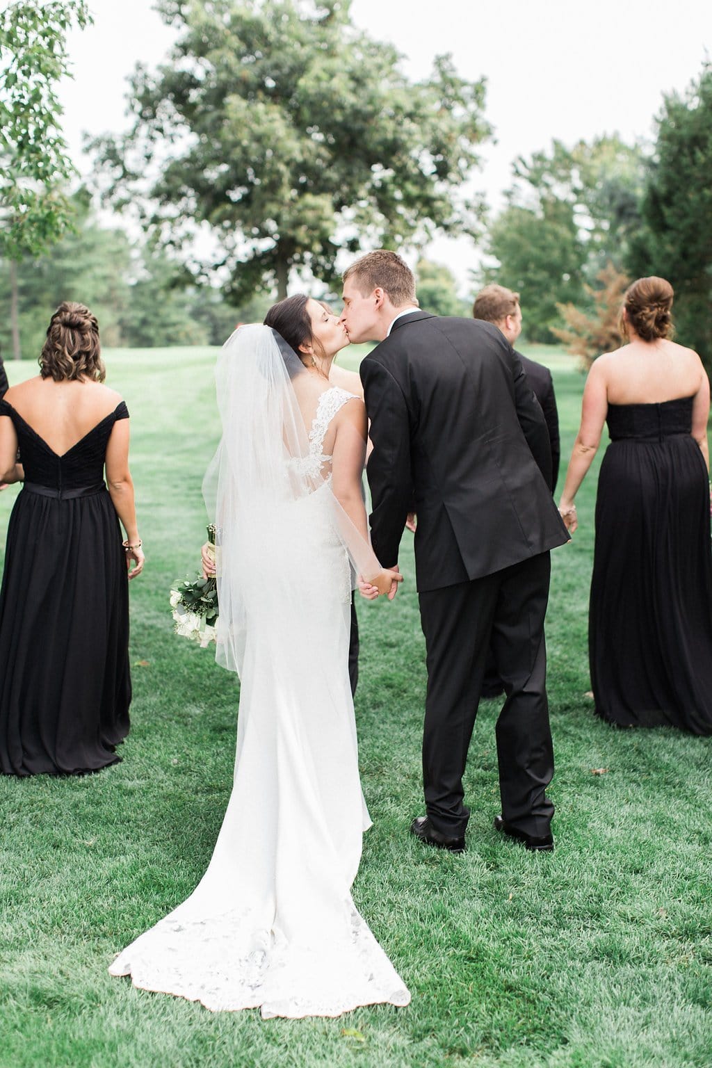 Lauren Renee - Pittsburgh Fine Art Wedding Photography Bride and groom kissing while holding hands and walking with bridal party on golf course