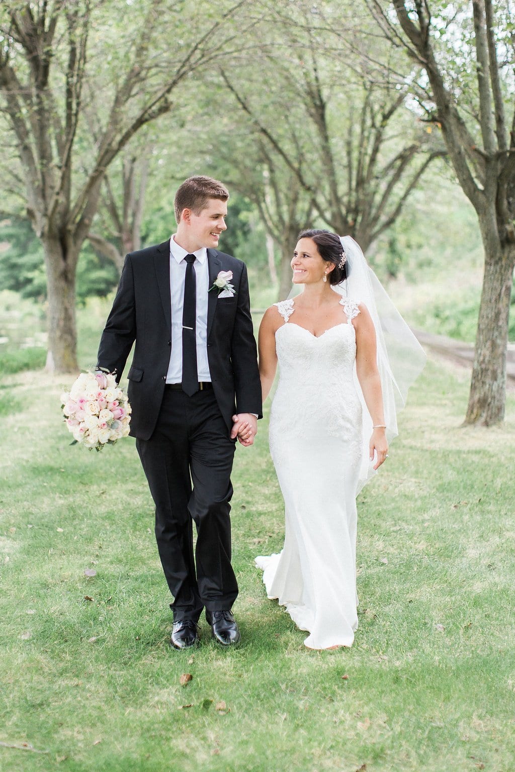 Lauren Renee - Pittsburgh Fine Art Wedding Photography Groom holding bride's bouquet as they walk together holding hands and looking at each other