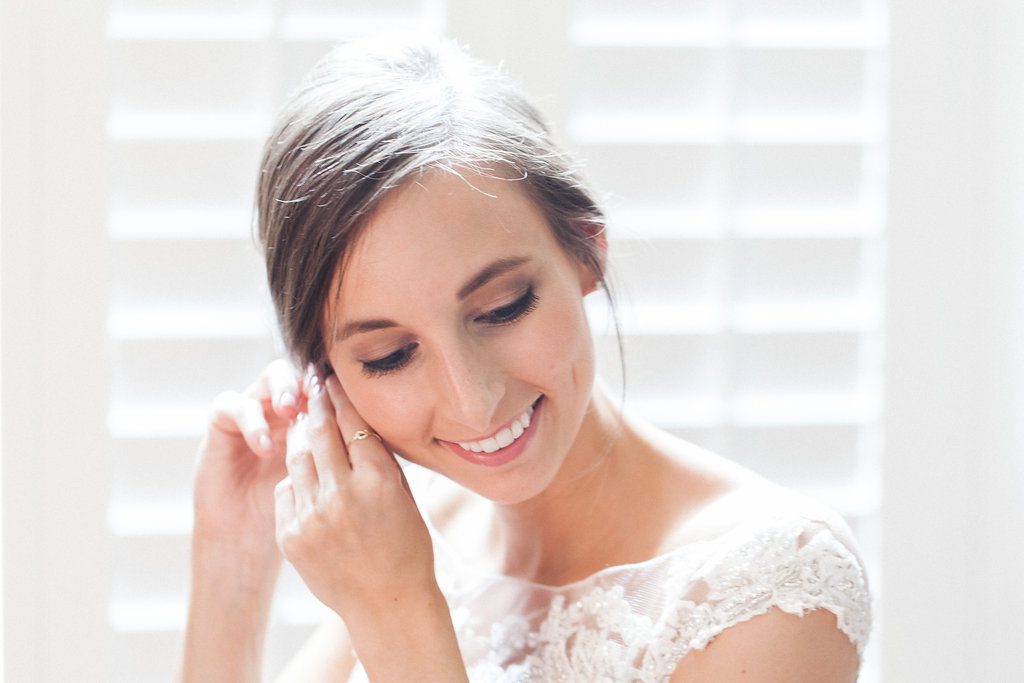 Bride putting her earrings on while getting ready for her wedding day