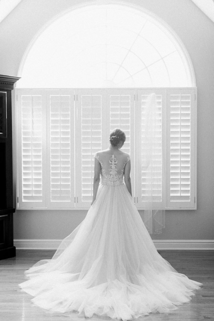 Black and white photograph of bride getting ready for her wedding in her dress