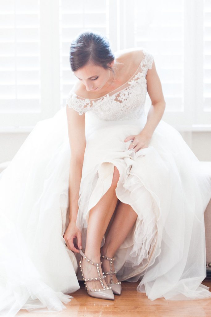 Bride putting on her Valentino Rockstud shoes while getting ready before her wedding