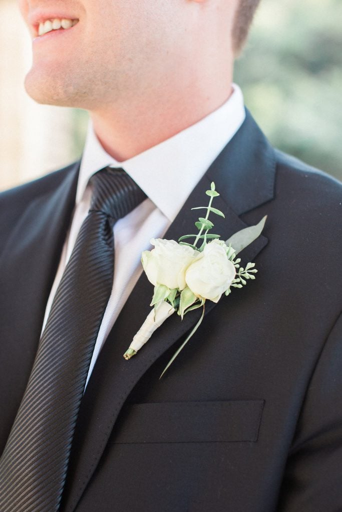 Groom getting ready with boutonnière outside the church