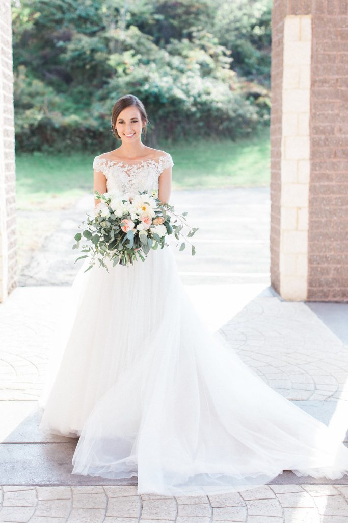 Bride holding her blush pink and white bouquet outside the church