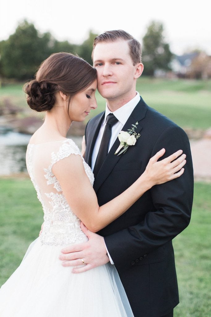 Bride and Groom embracing in a romantic portrait on the golf course at sunset