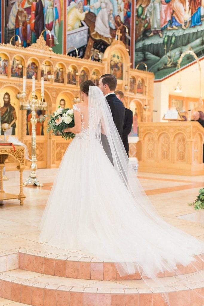 The bride and groom walking up to the alter at the All Saints Greek Orthodox Church