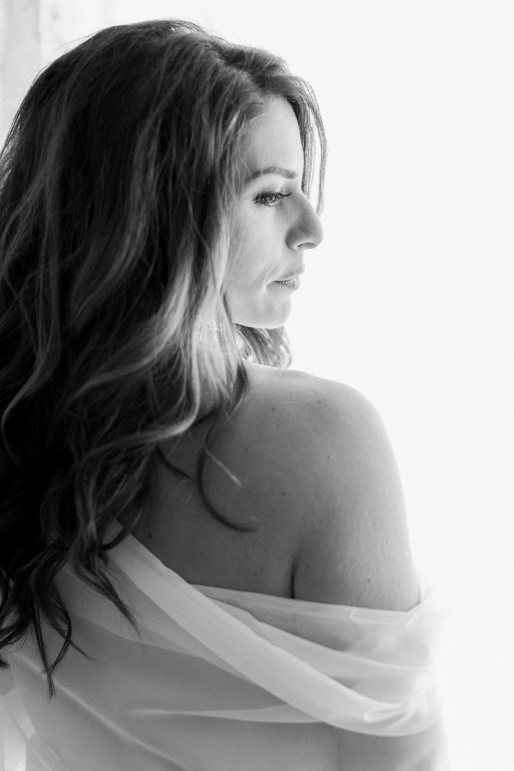 Lauren Renee Photography Side view of bride during boudoir session using window light in black and white