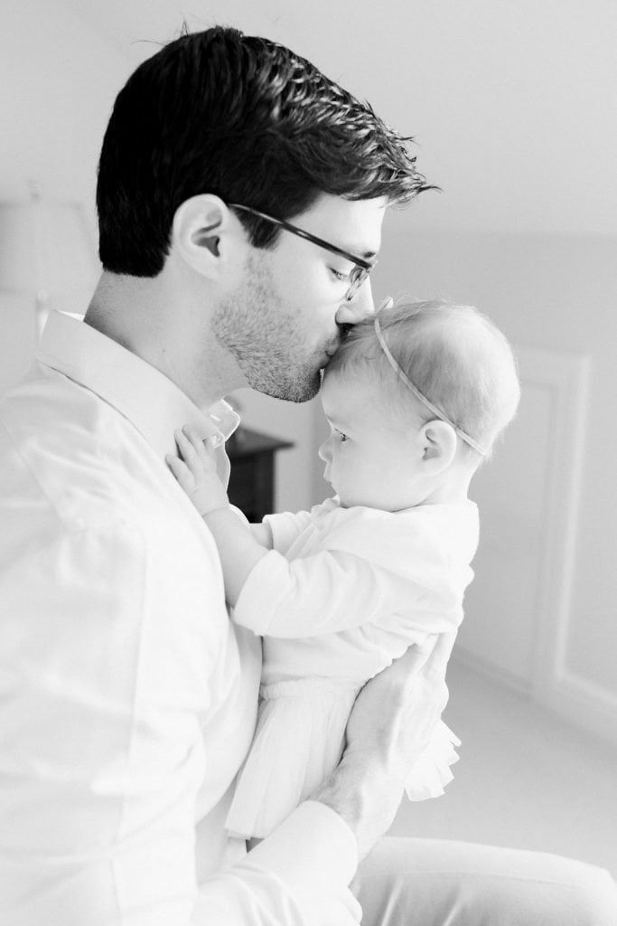 Dad kissing baby on the head for a sweet moment black and white photo