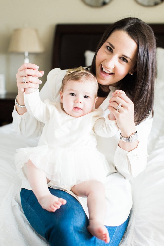 Mom holding daughters arms in the air for a fun photo on the bed