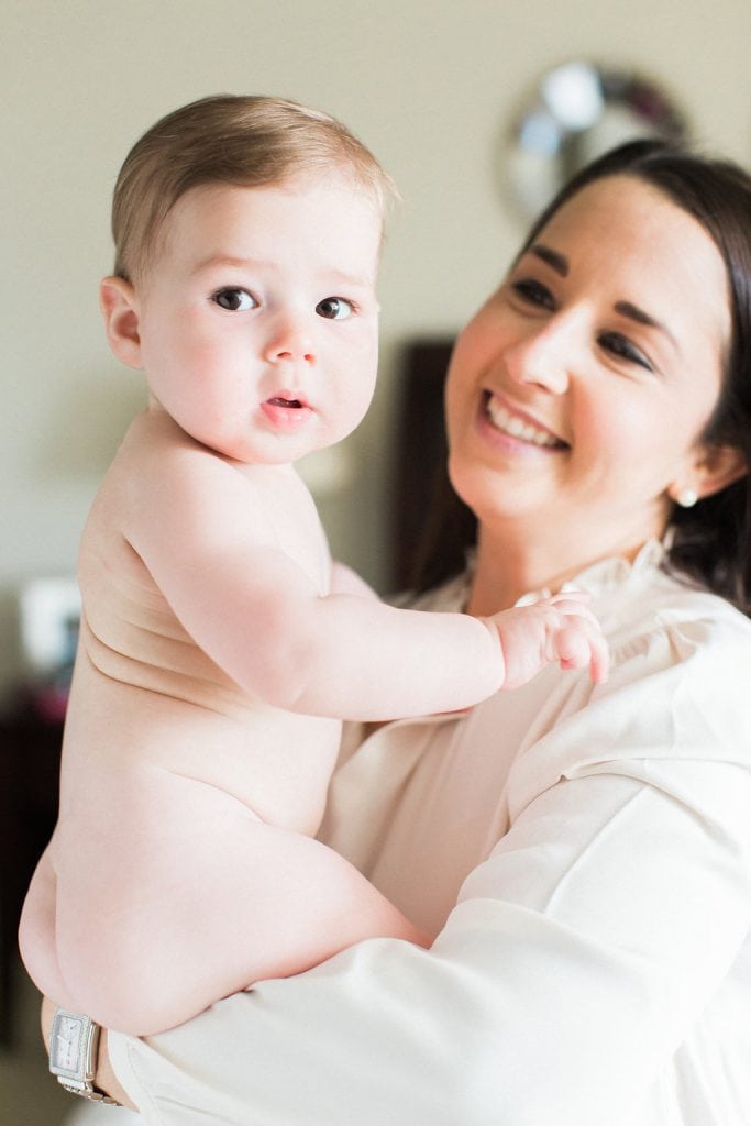 Mother holding naked baby while smiling