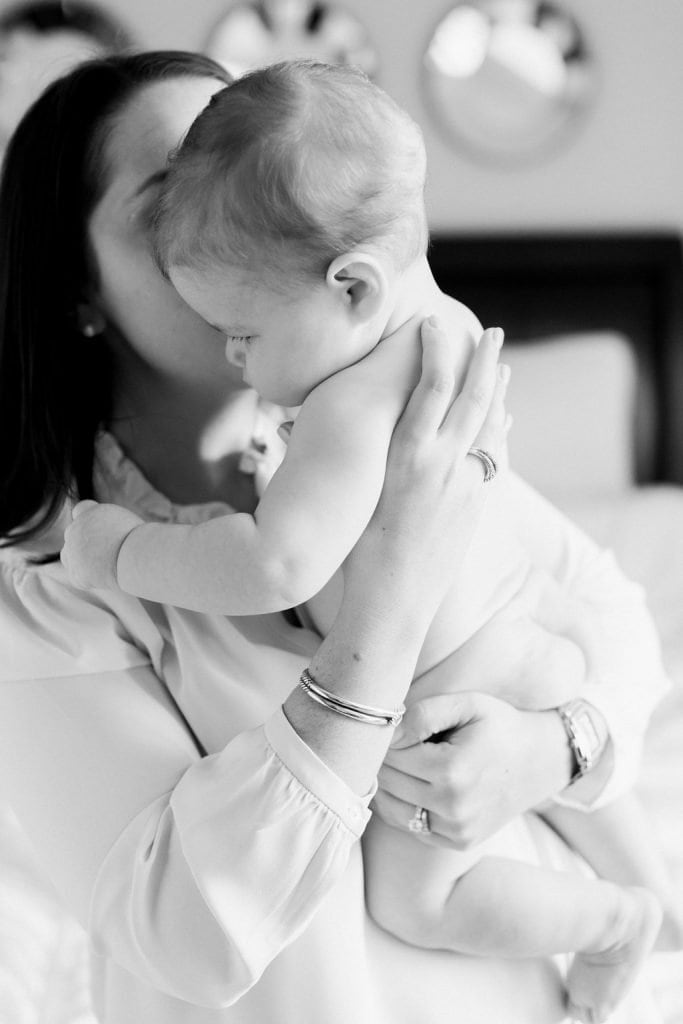 Mom kissing baby on the cheek in a black and white photograph