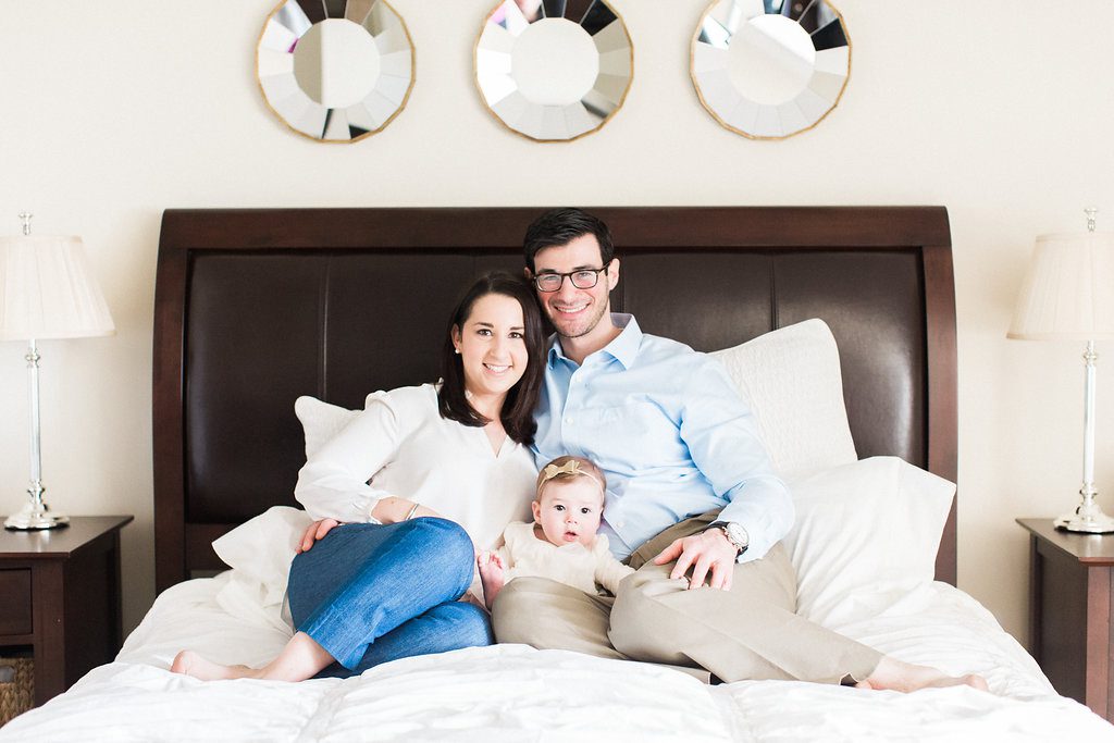 In home lifestyle family photograph in master bedroom parents with baby