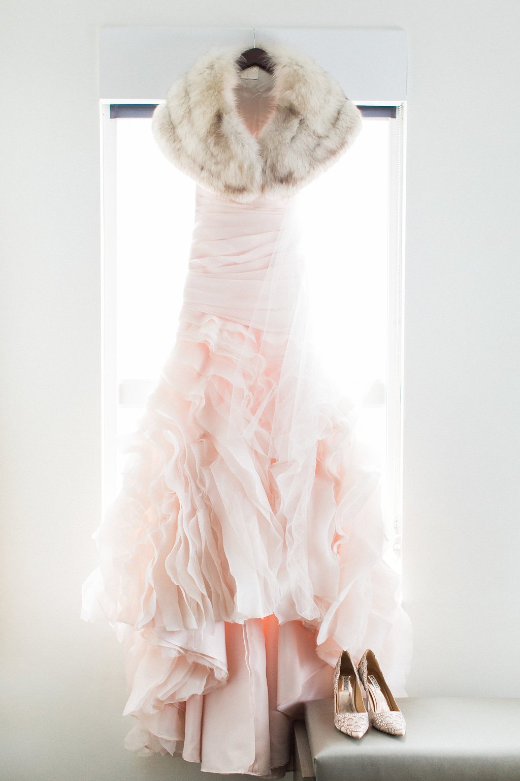 Pittsburgh Wedding Photography - Lauren Renee Photography Photograph of blush pink wedding dress hanging in hotel room with fur shawl and badgley mischka bridal shoes