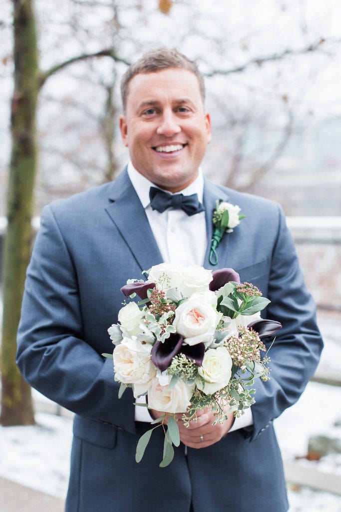 Photo of the groom holding the bride's bouquet