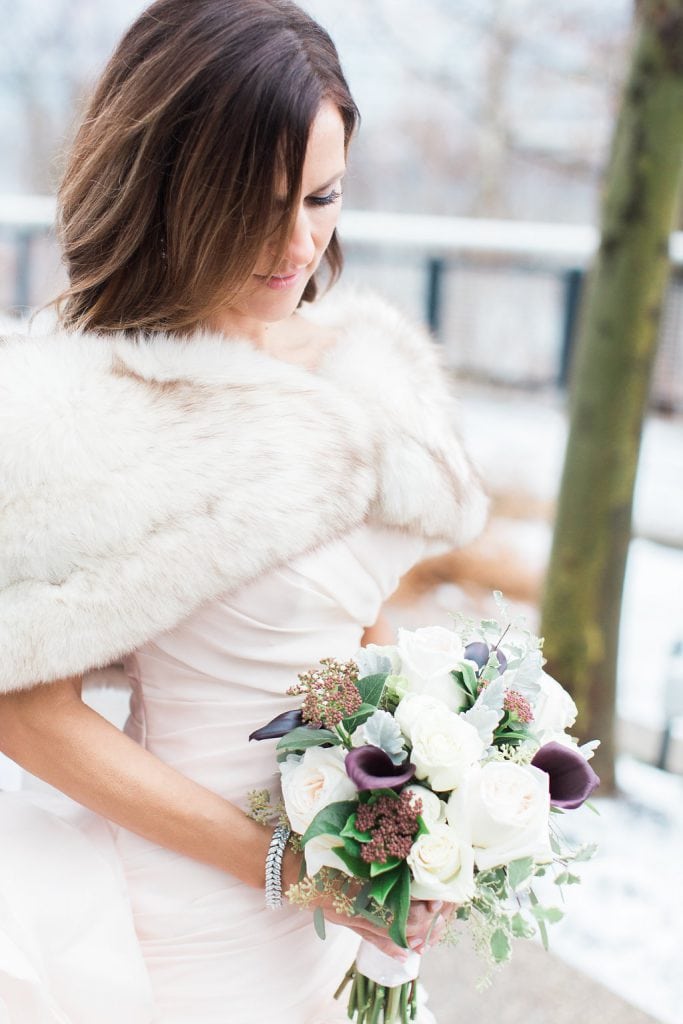 Photo of the bride out in the snow with fur shawl and bouquet