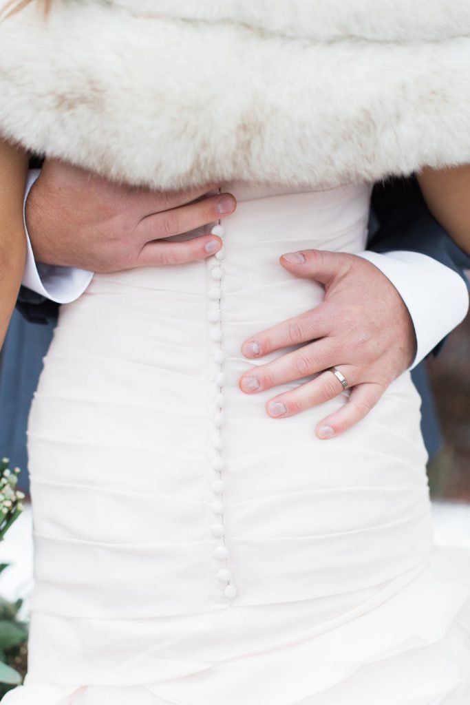 Portrait of groom grabbing bride's waist showing wedding ring