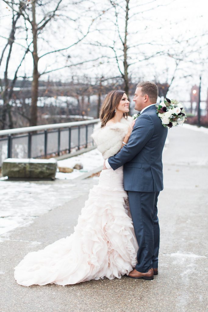 Bride wearing a blush pink wedding gown and fur shawl groom in navy blue suit