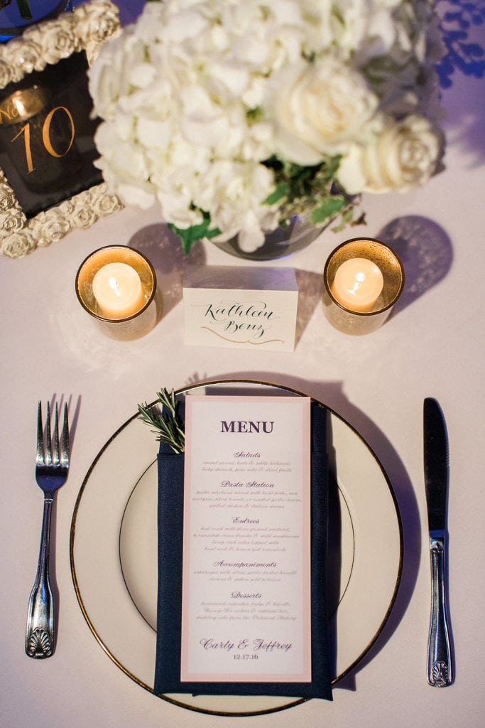 Table setting with calligraphy escort card, dinner menu, and a sprig or rosemary