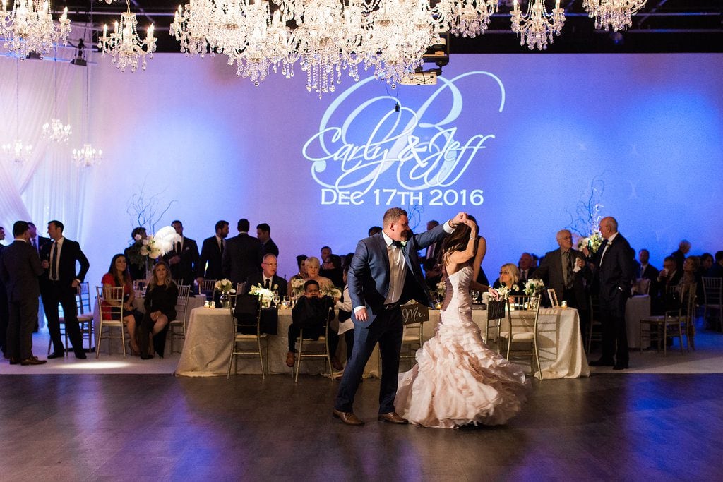 Bride and groom dancing under chandeliers at wedding reception