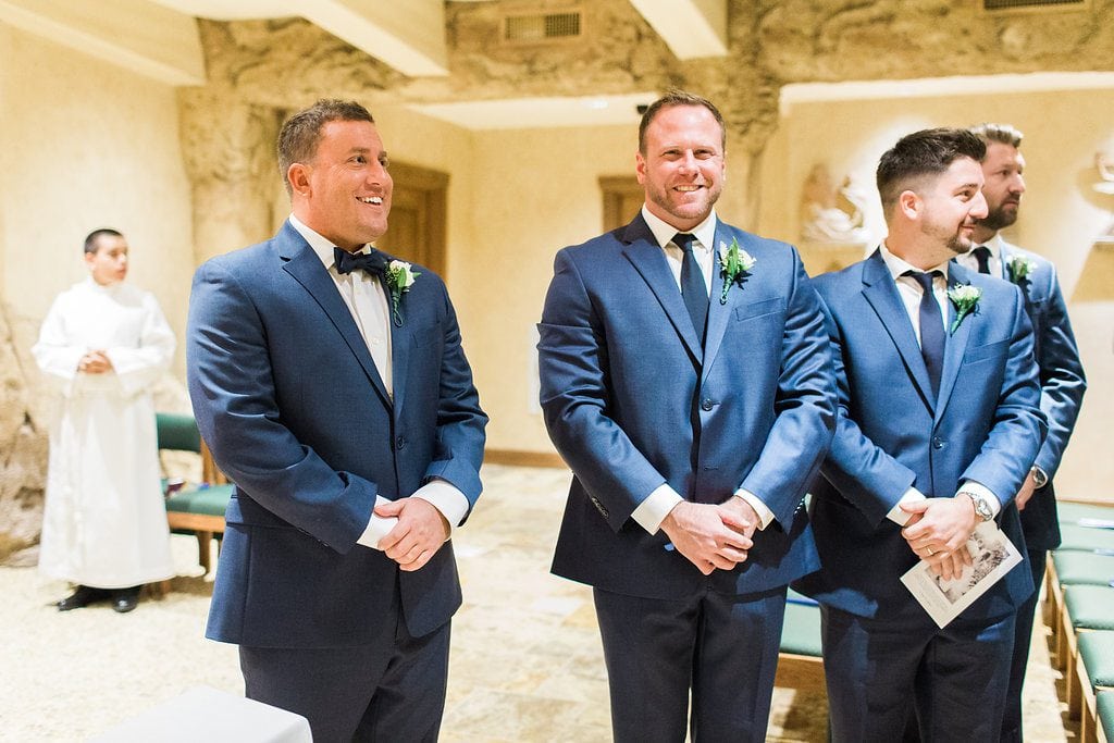 Groom seeing the bride for the first time walking down the aisle in the grotto of Saints John and Paul Roman Catholic Church