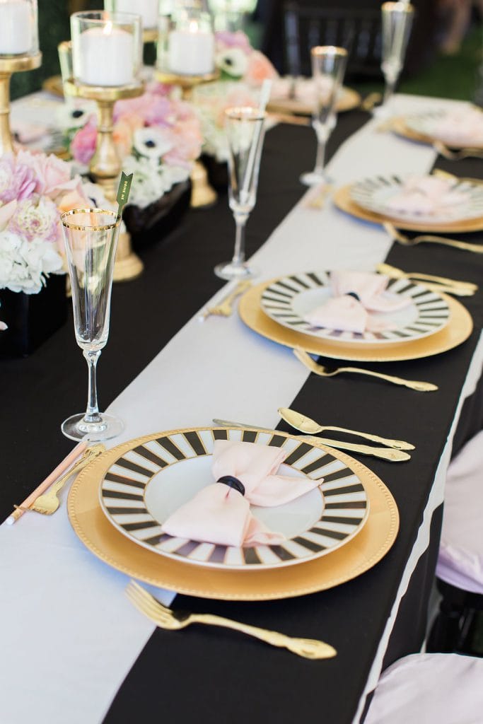 place setting with candles and flowers with black and white kate spade plate and gold accents