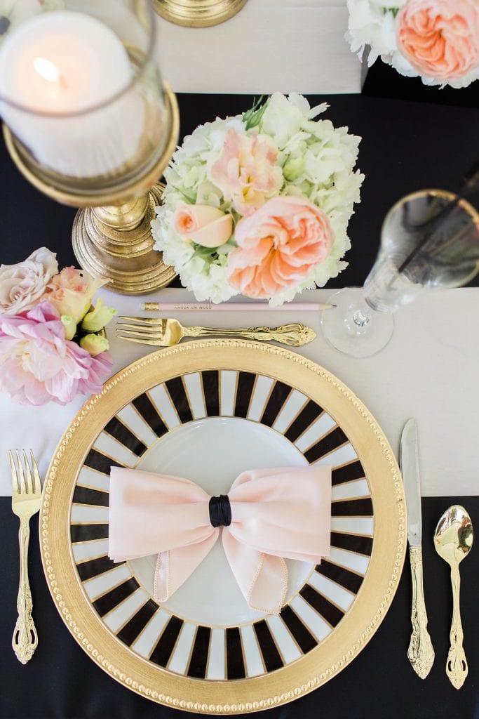 place setting with candles and flowers with black and white kate spade plate and gold accents