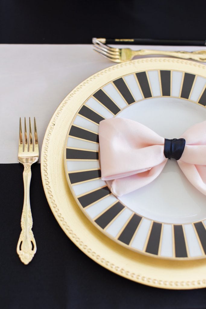 black and white kate spade plate with gold charger and pink bow napkins