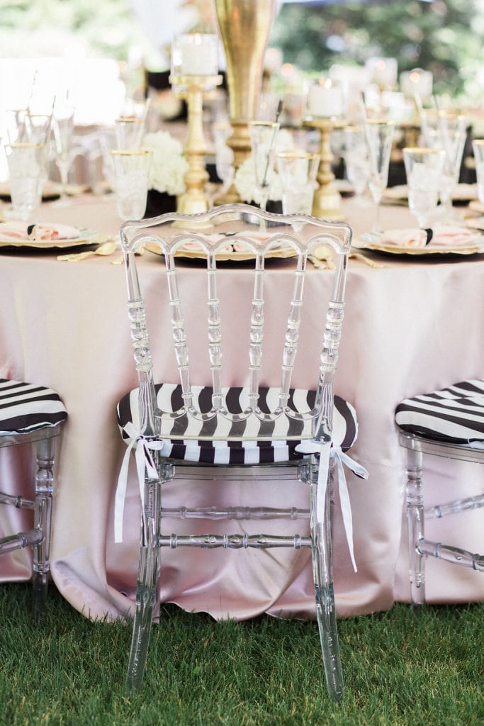 acrylic chairs with black and white cushions and pink table cloth