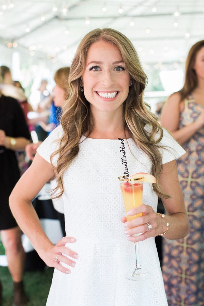 bride wearing white and holding a cocktail in gold rimmed glass