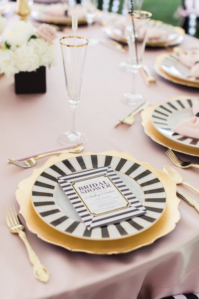 black and white plate with gold charger and pink table cloth