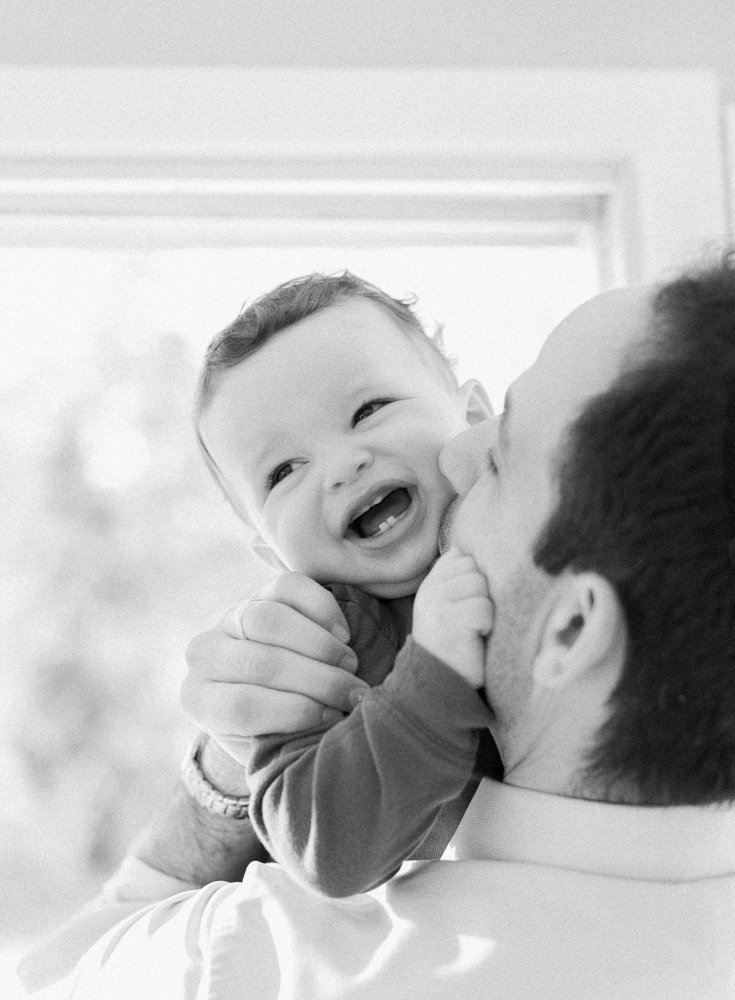 Dad kissing baby during film photography session black and white - Spring Family Portraits New Rochelle