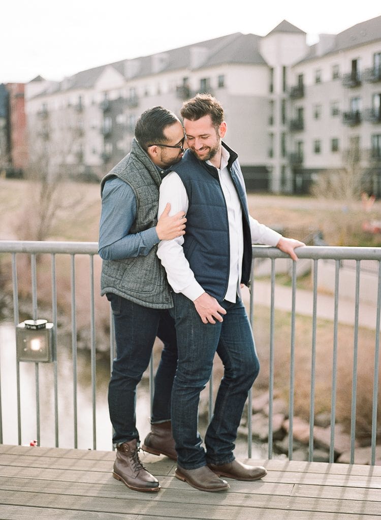 Estes Park Engagement Photography Session - gay men embracing on a bridge in downtown denver