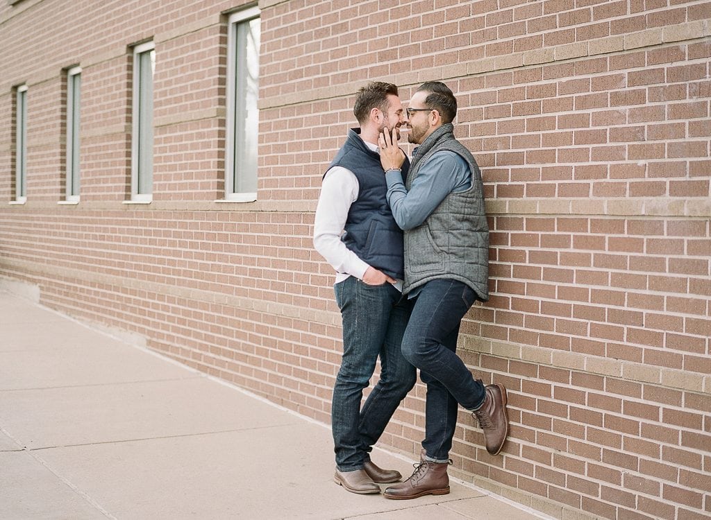 Estes Park Engagement Photography Session - two men snuggling against and brick wall