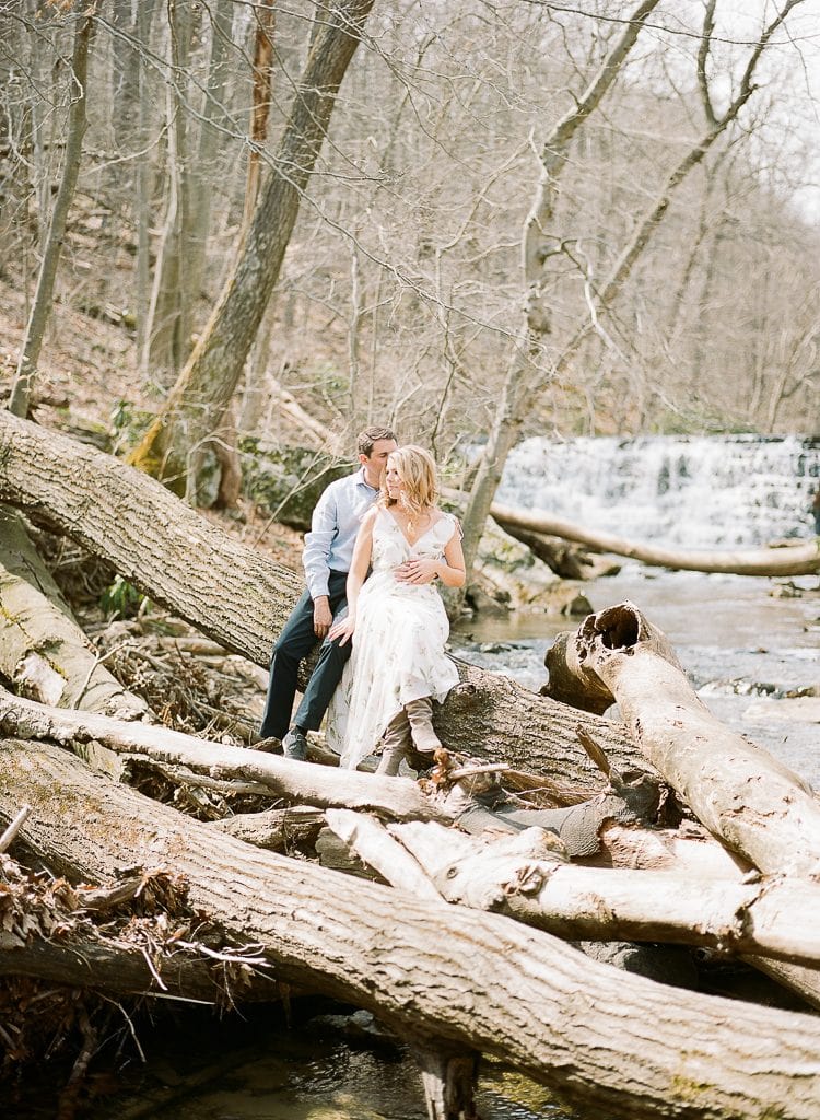 Seven Springs Engagement Photography - bride and groom sitting on a log near the stream