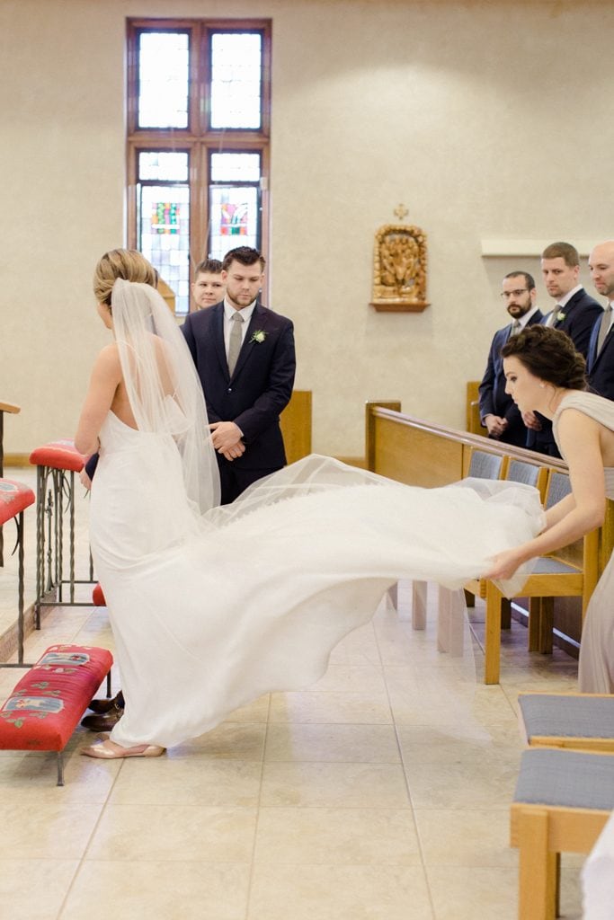 The Pennsylvanian Wedding fluffing bride's paloma blanca dress at St. Bede's Church