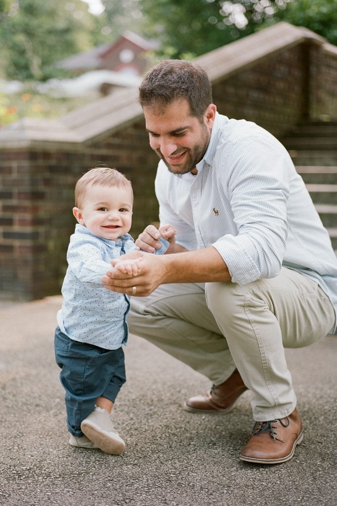 Dad holding his son's hand while crouching near him during Family Session at The Walled Garden