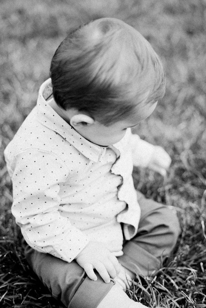 Black and white photo of baby playing in the grass