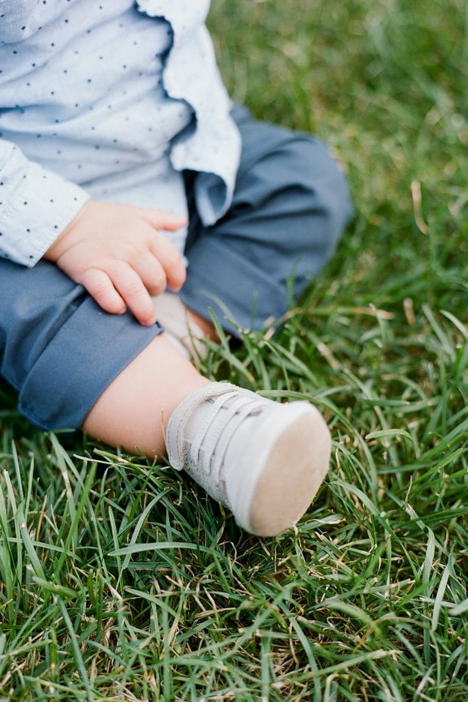 Baby shoes and hands on the grass