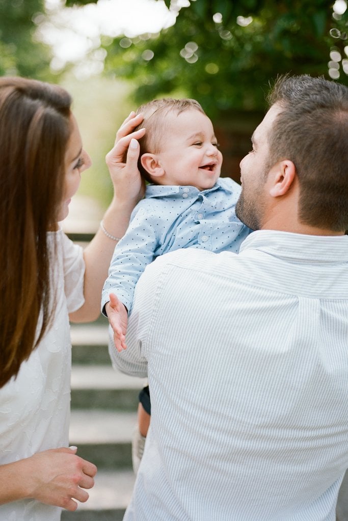 Mom and Dad kissing and tickling baby boy during Family Session at The Walled Garden