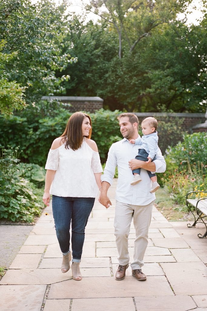 Mom and dad holding hands while walking and holding the baby