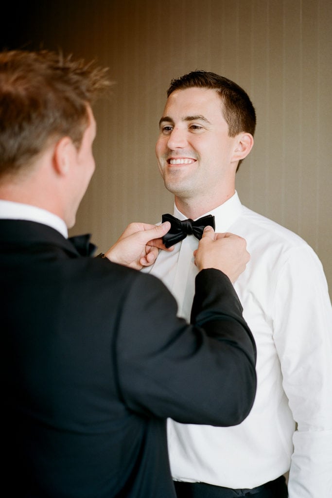 Groom putting on his finishing touches and fixing his bowtie