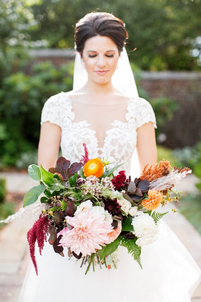 Bride holding her fall colored bouquet from the Farmer's Daughter