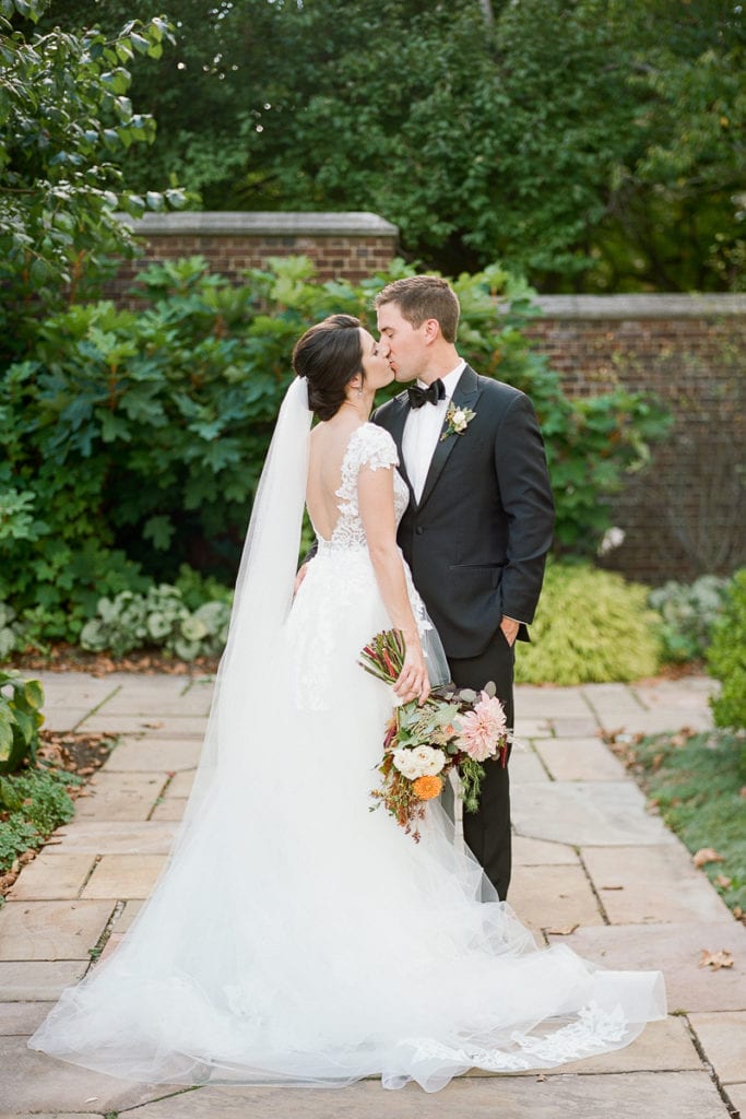 Bride and groom standing in the walled garden kissing