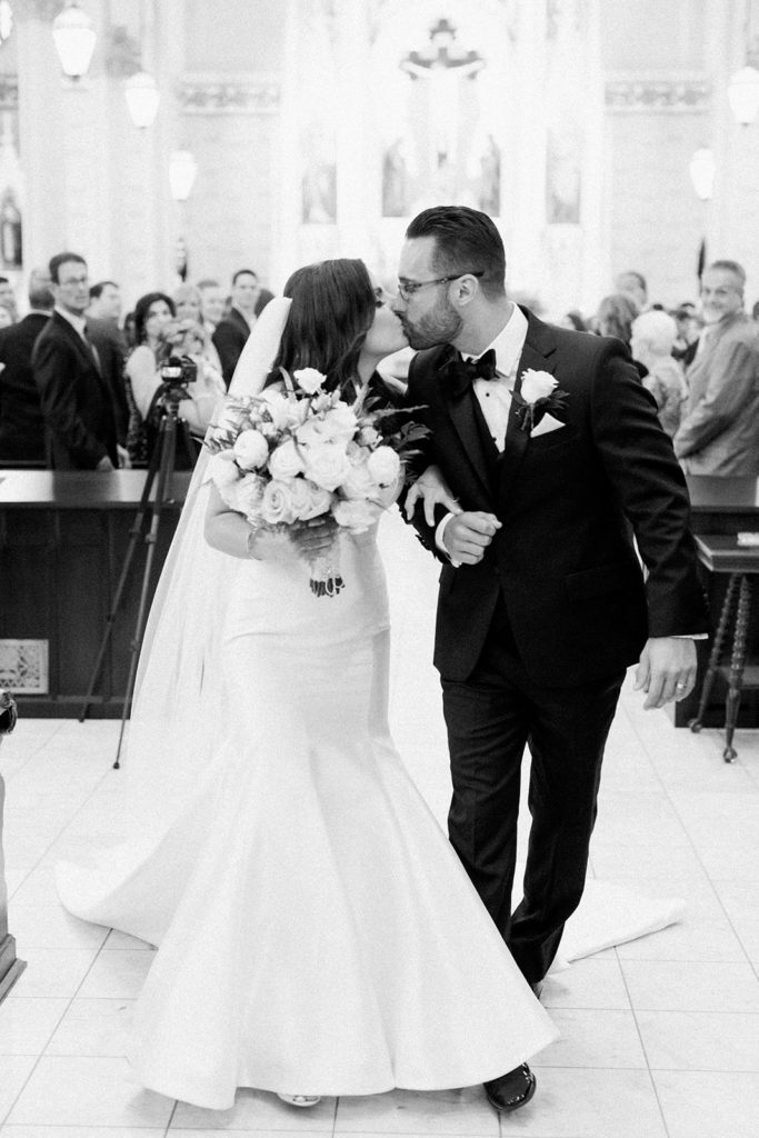 Bride and groom kissing at the end of the aisle