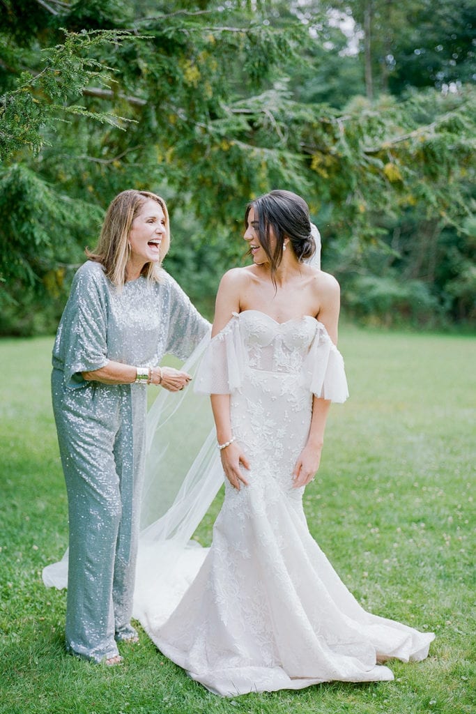 Mother of the bride helping her daughter into her Berta Bridal Wedding Gown