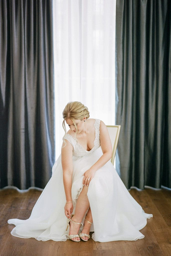 Bride putting on her Badgley Mischka wedding shoes