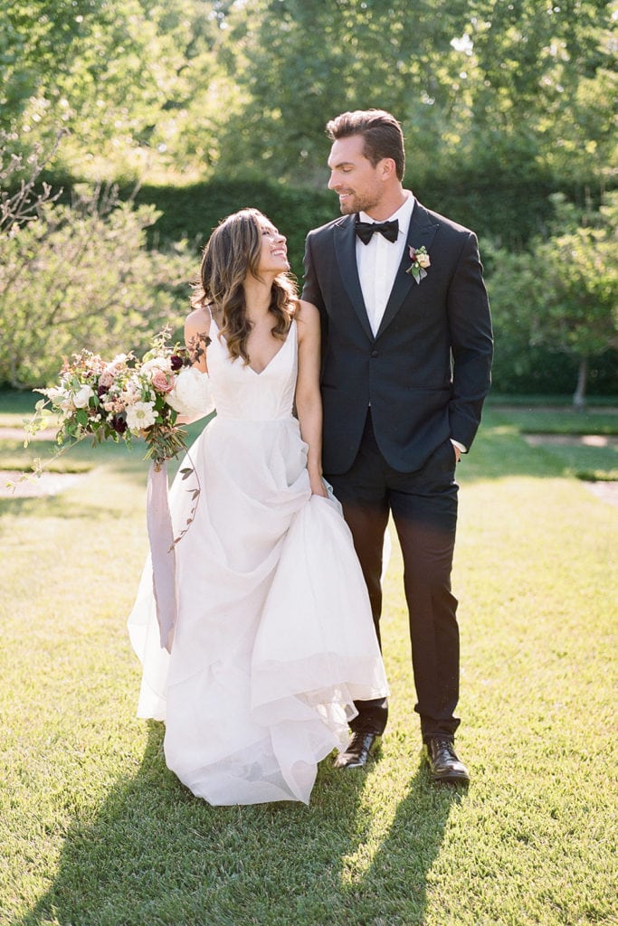 Couple walking:Ceremony Arch with flowers by Emily Reynold Design: Kestrel Park California Wedding Inspiration Styled Shoot captured by Pittsburgh Wedding Photographer Lauren Renee