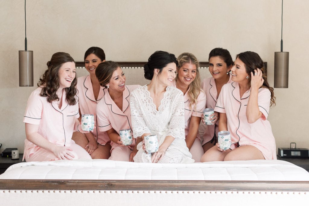 Bride with her bridesmaids sitting on a bed