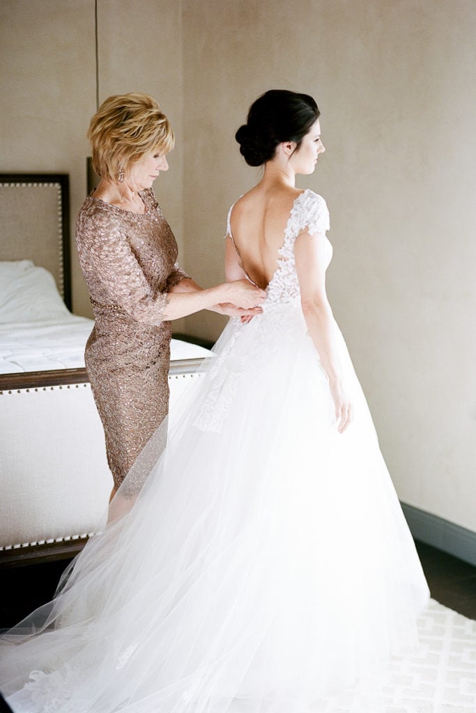 Mother of the bride helping her daughter into her wedding dress
